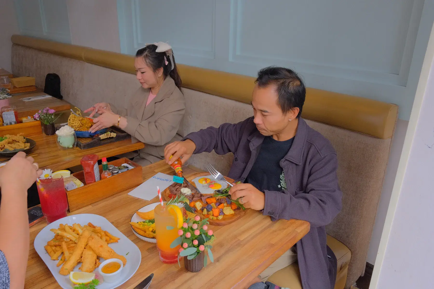 Two guests at a booth with a full table of brunch plates and drinks