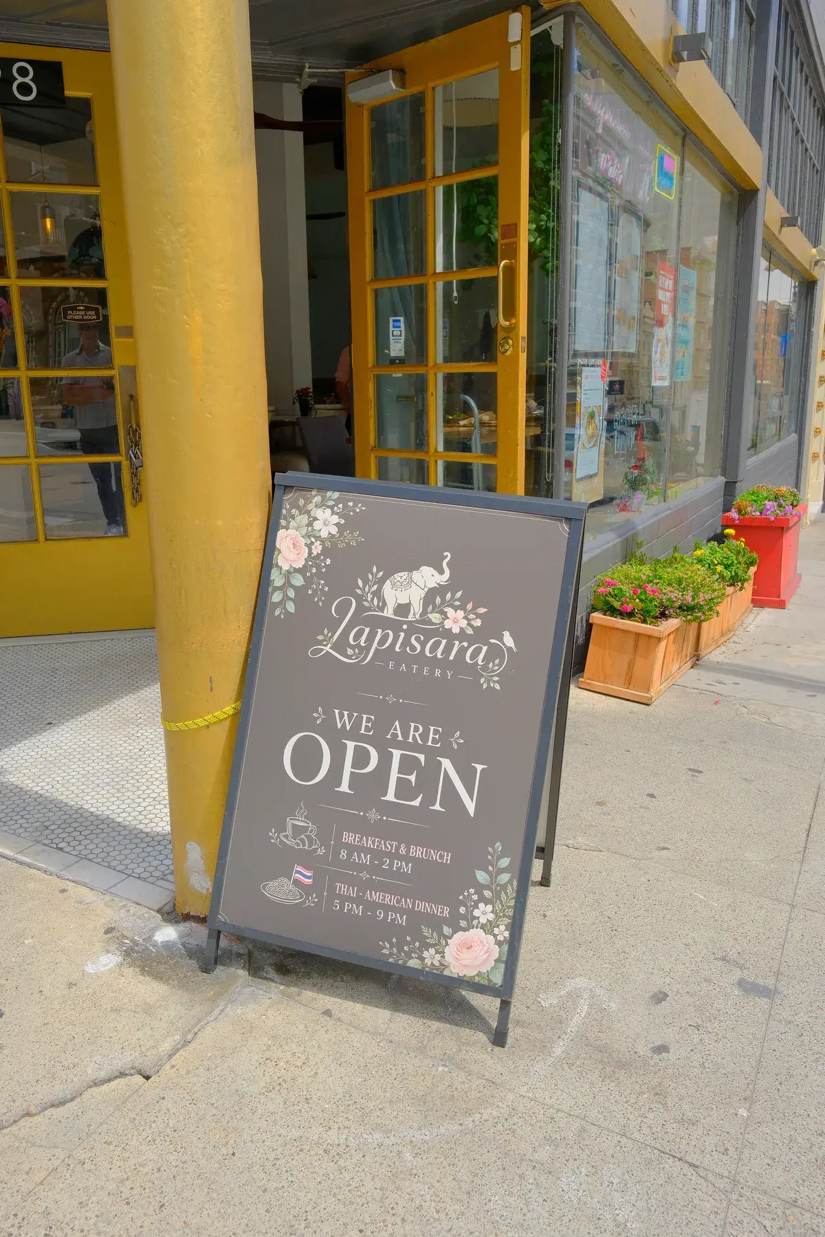 The Lapisara open sign on the pavement outside the yellow storefront