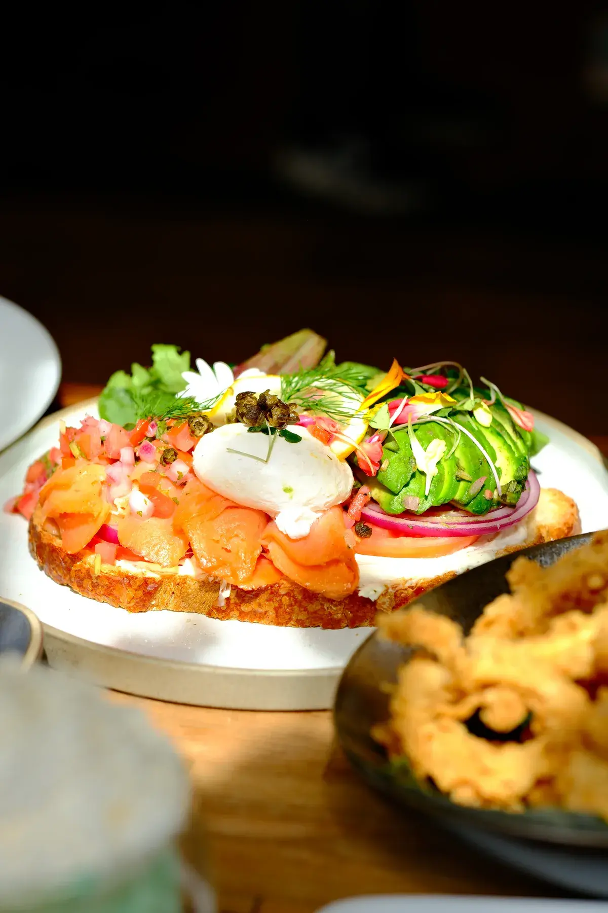 Smoked salmon toast with a poached egg, avocado, tomato and red onion