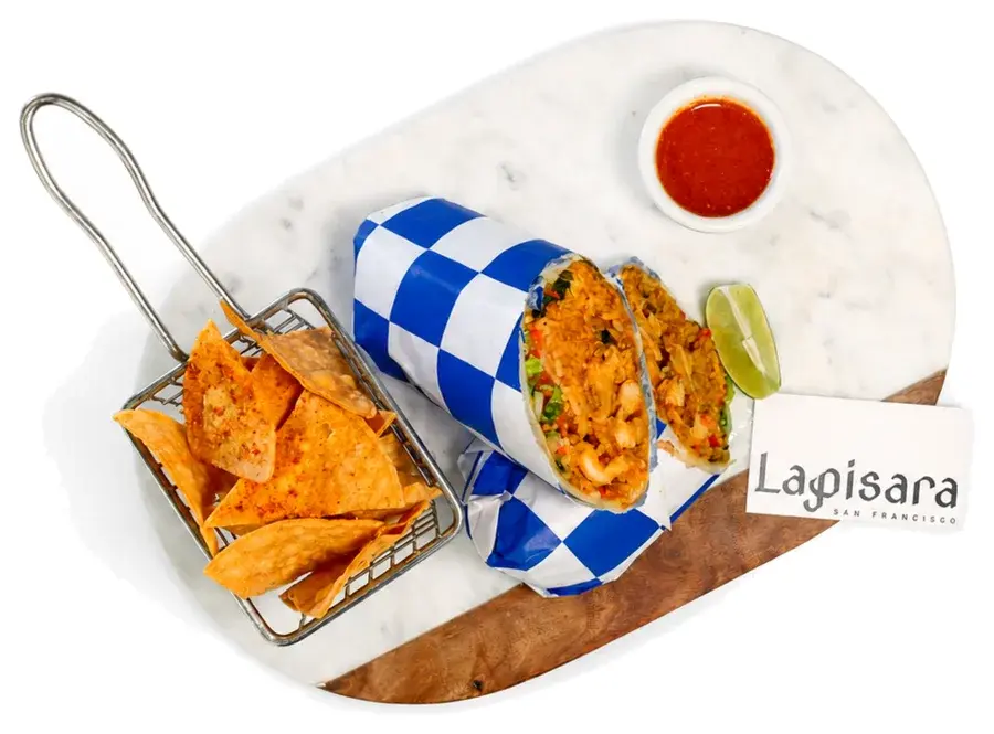 A wrapped burrito with tortilla chips and dipping sauce beside a Lapisara card
